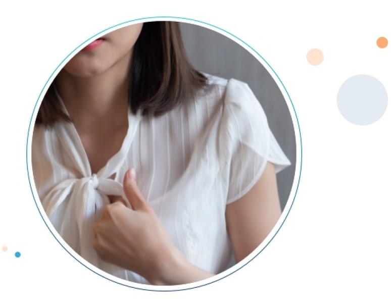 Una mujer con una blusa elegante toca su pecho con un gesto de dolor gracias al reflujo ácido.