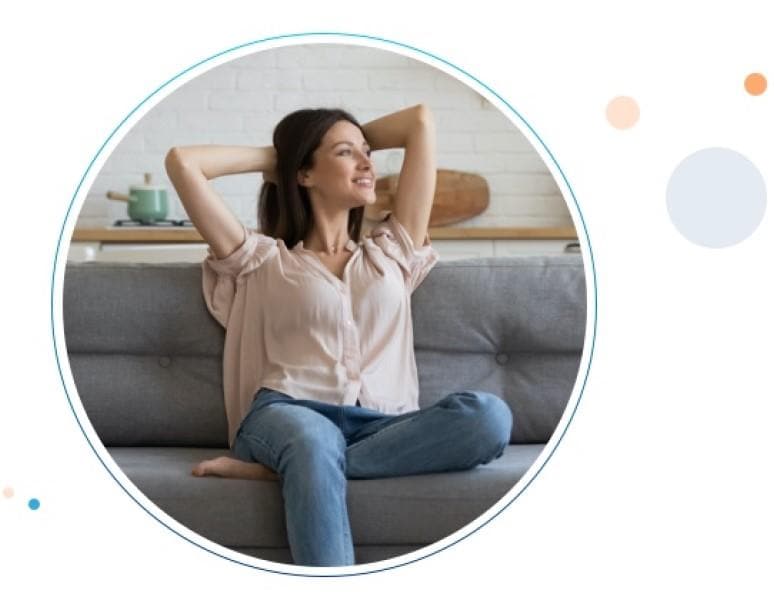 Una mujer feliz sentada en un sillón con sus brazos extendidos de felicidad.