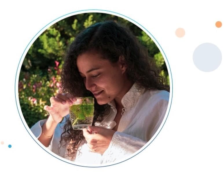 Una mujer sentada en su jardín, disfrutando de un te herbal que ayuda a trataminento de la acidez.