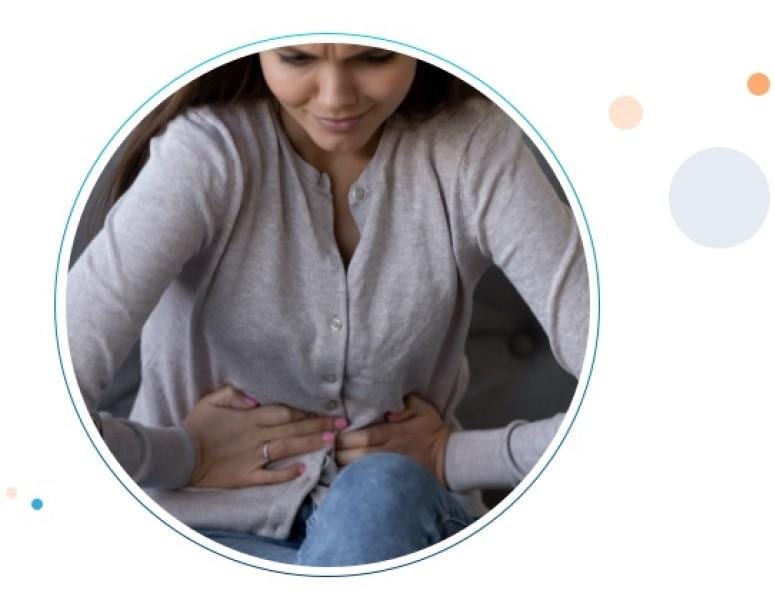 Una joven mujer tomando su estómago con gesto de dolor causado por indigestión.