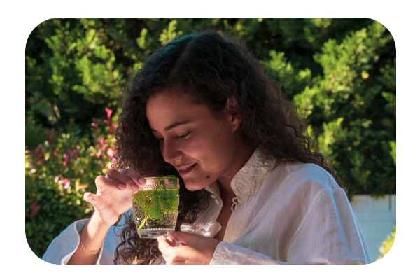 A young woman sitting in her garden, enjoying a freshly made herbal tea which is good for heartburn.